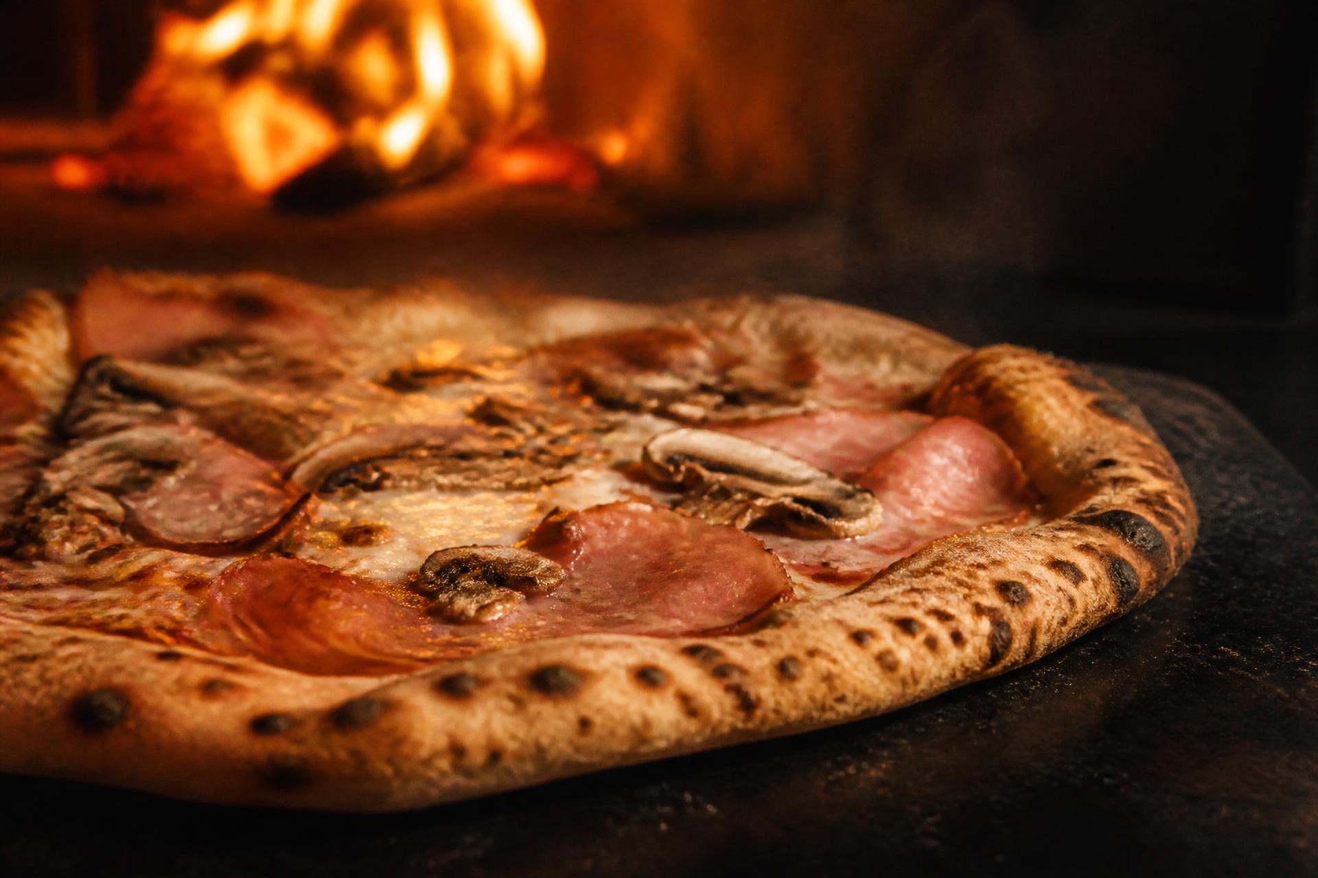 Nybakad pizza framför pizzaugnens eld